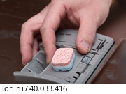A tablet for the dishwasher.The man lays the powder for the dishwasher. Стоковое фото, фотограф Александр Поташев / Фотобанк Лори