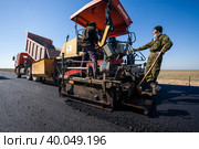 Kyzylorda province, Kazakhstan, April 29, 2012: Construction of West Europe-West China new highway. Dynapac road machine and dump truck unloads hot asphalt. Стоковое фото, фотограф Alexey Rezvykh / Фотобанк Лори