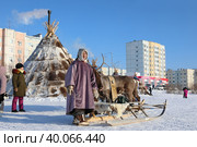 Женщина оленевод на фоне чума и городских зданий во время праздника День оленевода. Город Надым, Ямало-Ненецкий автономный округ (2023 год). Редакционное фото, фотограф Григорий Писоцкий / Фотобанк Лори