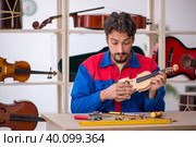 Young man repairing musical instruments at workshop. Стоковое фото, фотограф Elnur / Фотобанк Лори