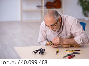 Old male repairman repairing musical instruments at workshop. Стоковое фото, фотограф Elnur / Фотобанк Лори