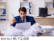 Young male employee and a lot of cut papers in the office. Стоковое фото, фотограф Elnur / Фотобанк Лори