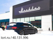 Вывеска с названием марки российских автомобилей  "Москвич" на здании автосалона мартовским снежным днем. Санкт-Петербург (2023 год). Редакционное фото, фотограф Виктор Карасев / Фотобанк Лори