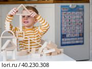 Маленький мальчик 3 лет играет в развивающий логистический конструктор. Детские деревянные игрушки. Монтессори для развития ребенка. Стоковое фото, фотограф Photojuli / Фотобанк Лори