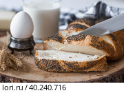 Классическая пшеничная коса или плетёнка с маком. Вкусный хлеб крупным планом. Свежеиспеченный хлеб на закваске с золотистой корочкой на деревянной доске. Контекст пекарни с вкусным хлебом. Кондитерские изделия. Стоковое фото, фотограф Photojuli / Фотобанк Лори