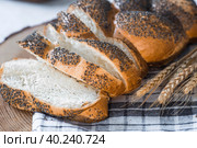Классическая пшеничная коса или плетёнка с маком. Вкусный хлеб крупным планом. Свежеиспеченный хлеб на закваске с золотистой корочкой на деревянной доске. Контекст пекарни с вкусным хлебом. Кондитерские изделия. Стоковое фото, фотограф Photojuli / Фотобанк Лори