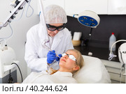 Professional beautician making laser resurfacing to female client face skin. Стоковое фото, фотограф Яков Филимонов / Фотобанк Лори