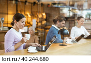 Young millennial woman sitting at table, using laptop and enjoing cup of tea in coffee house. Modern female lifestyle concept. Стоковое фото, фотограф Яков Филимонов / Фотобанк Лори
