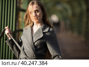 Красивая молодая женщина со светло-каштановыми волосами, развевающимися и растрепанными на ветру. Привлекательная женщина в сером пальто смотрит в сторону. Аллея в осеннем парке. Осенний сезон. Осеннее настроение. Стоковое фото, фотограф Андрей Степанов / Фотобанк Лори