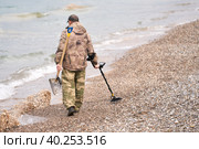 A man with a metal detector and a miser in his hands on the seashore. He's looking for lost jewelry. Selective focus. Стоковое фото, фотограф Роман Дзюбало / Фотобанк Лори