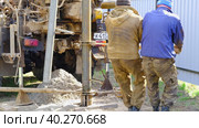Team of workers with drilling rig on car are drilling artesian well for water in ground. Insertion of metal casing pipe into ground, installation of individual drinking supply, June 28, 2022, Russia, Palaces. Редакционное видео, видеограф Ольга Симонова / Фотобанк Лори