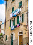 Laundry is dried on the windows of houses. Traditional Italian resort village, Liguria, Italy (2019 год). Стоковое фото, фотограф Илья Курлин / Фотобанк Лори