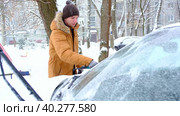 A man brushes snow from a car after a snowfall. A hand in a mustard jacket with a car broom on the white body. Winter weather conditions. Slow Motion. Стоковое видео, видеограф Ольга Симонова / Фотобанк Лори