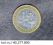 Реверс памятной 10-ти рублевой монеты (2005 г.) «Древние города России. Мценск». Изображена панорама  и герб города: четыре золотых, уложенных крестом и перевязанных красными лентами снопа, в зеленом поле геральдического щита. Изолировано на темном фоне. Стоковое фото, фотограф Сергей Елизарьев / Фотобанк Лори