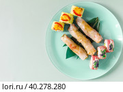 Три спринг-ролла с начинкой из морепродуктов и яркие роллы на светлой тарелке. Стоковое фото, фотограф Лозовая Людмила / Фотобанк Лори