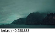 Calm ocean landscape with gray storm clouds on sky. Fog covered high sea cliffs on shore. Mystical foggy haze inspires fear and greatness. Стоковое видео, видеограф Ольга Сухарева / Фотобанк Лори