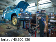 Автомеханик в гараже ремонтирует двигатель советского ретроавтомобиля Москвич-403 (2020 год). Редакционное фото, фотограф Виктор Карасев / Фотобанк Лори