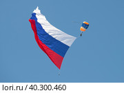 Парашютист с большим российским флагом в голубом безоблачном небе. Фрагмент открытия авиационного шоу МАКС-2019. Редакционное фото, фотограф Виктор Карасев / Фотобанк Лори