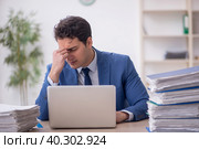 Young male employee and too much work in the office. Стоковое фото, фотограф Elnur / Фотобанк Лори