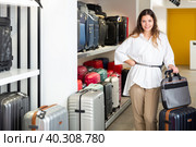 Happy woman chose suitcase in haberdashery store. Стоковое фото, фотограф Яков Филимонов / Фотобанк Лори