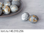 Stylish grey Easter eggs made of marble and concrete with a golden potala on a grey background. Coloring eggs with natural dye karkade tea. Environmental friendliness. Naturalness. The concept of a happy Easter. Стоковое фото, фотограф Photojuli / Фотобанк Лори