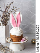 Beautiful stylish still life. Easter cake with rabbit (hare) ears, meringue, marshmallows, Easter eggs and willow branches and on a light concrete background. Happy Easter. Стоковое фото, фотограф Photojuli / Фотобанк Лори