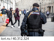 Сотрудник полиции патрулирует улицу и обеспечивает безопасность на Никольской улицы в центре города Москвы, Россия (2023 год). Редакционное фото, фотограф Николай Винокуров / Фотобанк Лори