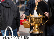 Russia, the City of Vidnoye, April 15, 2023. Easter service. The priest sprinkles people and Easter treats with holy water at the entrance to the temple. People go to sanctify eggs and cakes. Стоковое фото, фотограф Photojuli / Фотобанк Лори
