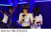 Cheerful emotional young couple in VR headsets fully immersed in game, actively engaged in virtual reality world, manipulating objects or shooting targets with joysticks in hands. Стоковое видео, видеограф Яков Филимонов / Фотобанк Лори