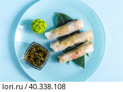 Спринг-роллы с начинкой из морепродуктов и темным соусом на светлой тарелке крупным планом. Стоковое фото, фотограф Лозовая Людмила / Фотобанк Лори