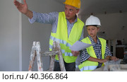 Father and son in yellow vest and protective helmet discuss drawings of renovated premises in cottage in a laptop. Стоковое видео, видеограф Яков Филимонов / Фотобанк Лори