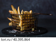 French fries in a metal basket with salt on a stylish board on a dark background. Fried potatoes. The concept of fast food and junk food. Стоковое фото, фотограф Photojuli / Фотобанк Лори