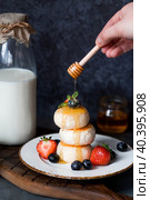 Cottage cheese pancakes, Russian cheesecakes with fresh blueberries, strawberries, honey and mint leaves on a stylish wooden board on a dark background. Natural products. Healthy and delicious breakfast. Стоковое фото, фотограф Photojuli / Фотобанк Лори