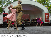 Молодые люди танцуют вальс на эстраде в Саду Эрмитаж в рамках мероприятия Бал Победы "В шесть часов вечера…" во время празднования Дня Победы 9 мая в Москве, Россия (2023 год). Редакционное фото, фотограф Николай Винокуров / Фотобанк Лори