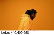 Young african guy in yellow hoodie laughing against yellow background. Стоковое видео, видеограф Сергей Толмачёв / Фотобанк Лори