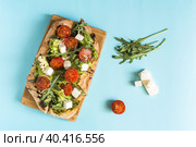 Пицца с сыром, помидорами, капустой и рукколой и  ингредиенты из которых она приготовлена на светло-голубом фоне. Стоковое фото, фотограф Лозовая Людмила / Фотобанк Лори