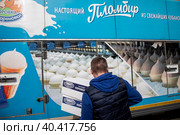 Водитель достает из грузового автомобиля коробки с мороженным бренда "Коровка из Кореновки" у магазина в центре города Москвы, Россия (2023 год). Редакционное фото, фотограф Николай Винокуров / Фотобанк Лори