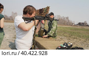 Berdsk, Russia, May 6, 2023. Weapon. An elderly woman picks up and takes aim from a Kalashnikov submachine gun with a collimator sight at a weapons exhibition. Hand held. Siberia. Редакционное видео, видеограф Сергей Медведев / Фотобанк Лори