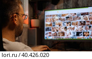 A bearded man with glasses looks at erotic pictures on the monitor at night. A close-up of his head. Sex addiction. Sex alone. Стоковое фото, фотограф Воловодов Владимир / Фотобанк Лори