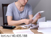 A woman at the table looks at receipts and bills. Стоковое фото, фотограф Alexandra Aleroewa / Фотобанк Лори