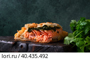 Pie with trout and spinach filling in puff pastry served on dark wooden board. Copy space. Стоковое фото, фотограф Оксана Чаюн / Фотобанк Лори