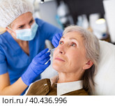 Cosmetologist making injections of botulotoxin in face of mature woman. Стоковое фото, фотограф Яков Филимонов / Фотобанк Лори