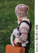 A little boy of 4 years old outdoors with a suitcase and a stuffed rabbit goes on a journey. A beautiful portrait of a child playing on the street. Стоковое фото, фотограф Photojuli / Фотобанк Лори