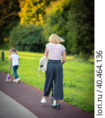 Mom rides a scooter with children in the park in summer. Russia Moscow September 24, 2020. Редакционное фото, фотограф Юрий Поздников / Фотобанк Лори