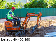 A worker on a minitractor rakes the earth with a bucket. Land works. Стоковое фото, фотограф Юрий Поздников / Фотобанк Лори