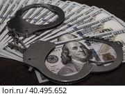 One hundred dollar bills and steel handcuffs close up. Стоковое фото, фотограф Артем Курутин / Фотобанк Лори