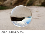 Glass ball lens lies on the sand of the sea shore. Стоковое фото, фотограф Артем Курутин / Фотобанк Лори