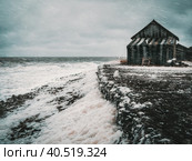 Winter storm day at sea. Dramatic seascape with a raging White sea and a fishing hut on the shore. Kandalaksha bay. Стоковое фото, фотограф Саблин Станислав / Фотобанк Лори
