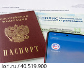 Персональные данные гражданина РФ: паспорт, медицинский полис, СНИЛС и телефон с электронным приложением Государственные слуги (2023 год). Редакционное фото, фотограф Татьяна Т / Фотобанк Лори