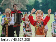 Russian folk traditions. Folk festivals. Children in beautiful Russian traditional outfits sing songs, dance and lead a round dance in Tsaritsyno Park. National Russian clothes. Sundresses and kokoshniks. (2023 год). Редакционное фото, фотограф Photojuli / Фотобанк Лори
